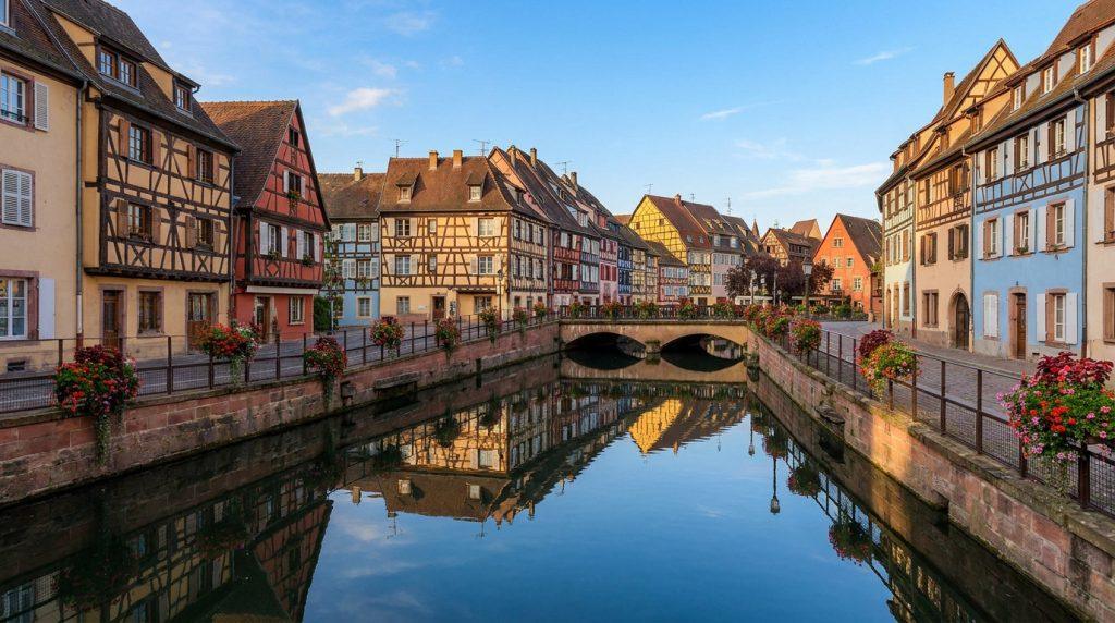 Maisons alsaciennes colorées à colombages le long d'un canal fleuri dans le quartier de la Petite Venise à Colmar.